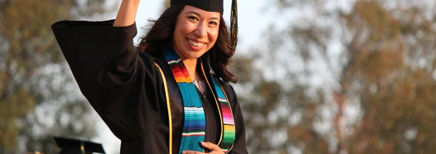Graduate in gown and cap holding up scroll