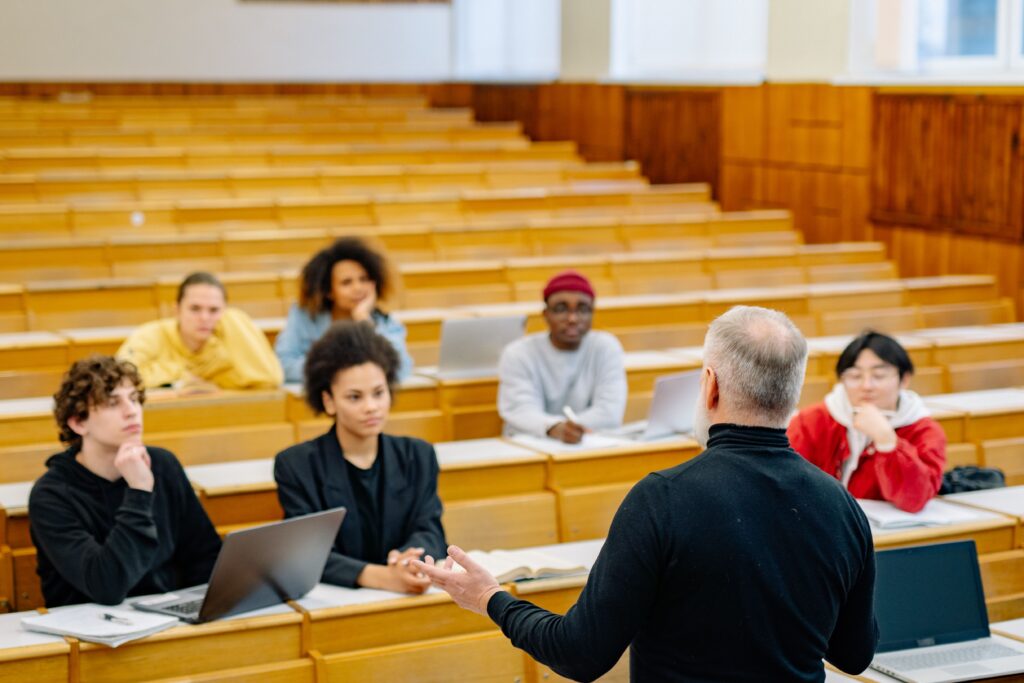 Students attending a lecture in a university classroom with an engaged professor.

